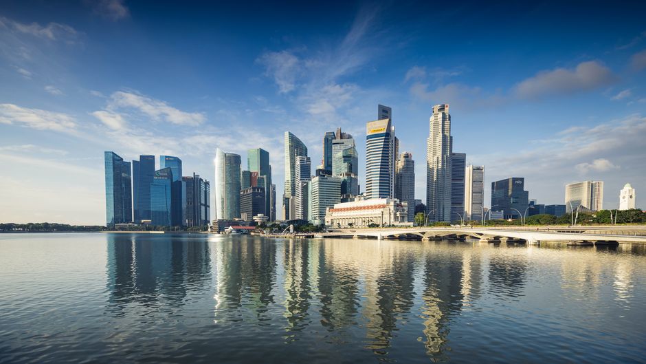 Capture of Singapore's modern skyline featuring reflective skyscrapers against a blue sky.