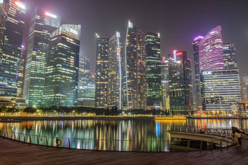 Vibrant night view of Singapore's Marina Bay skyline reflecting on the waterfront.