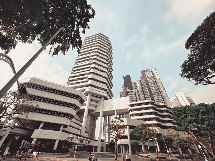 Dramatic low angle view of The Concourse building in Singapore against a blue sky, showcasing modern architecture.